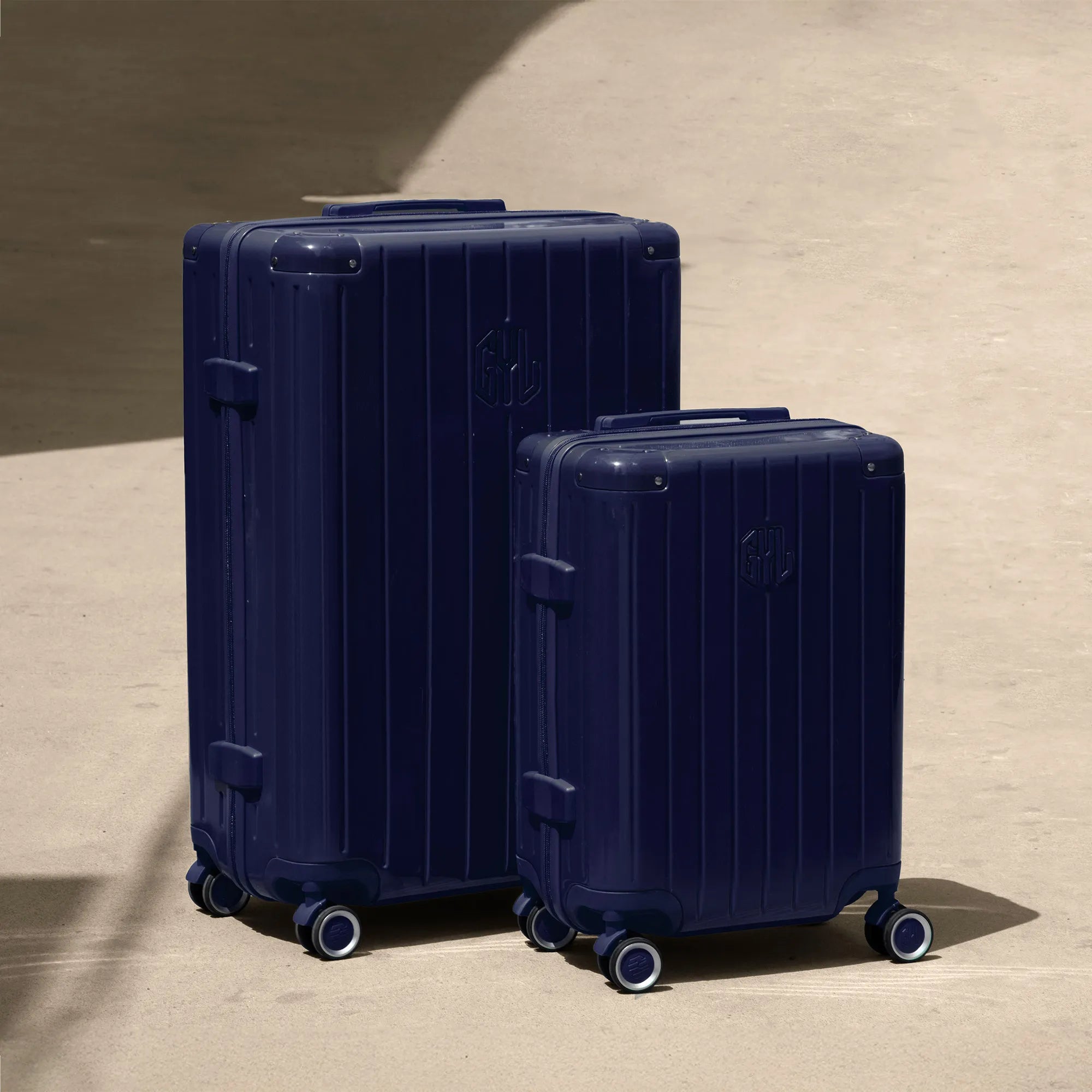 Ensemble de deux valises rigides GYL Intemporelle marine, tailles cabine et soute, posées sur sol béton.