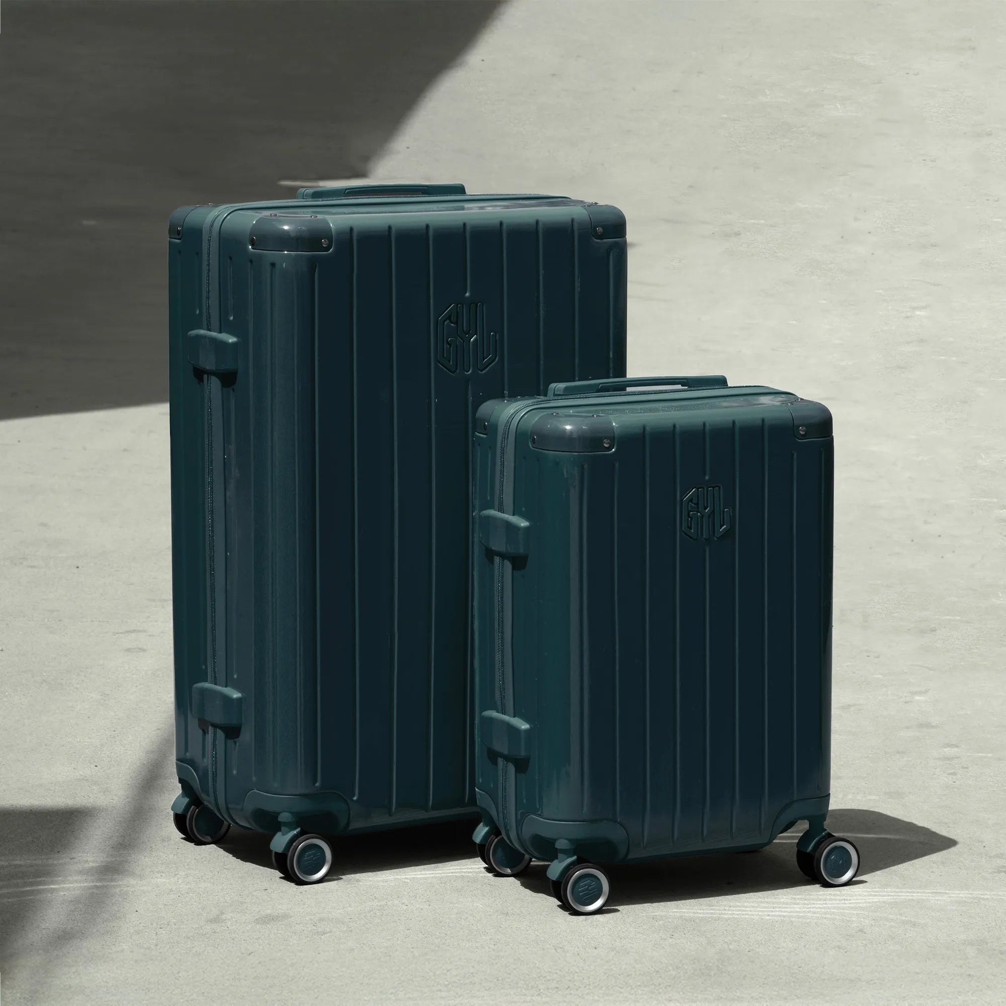 Ensemble de deux valises rigides GYL Intemporelle gris foncé, tailles cabine et soute, posées sur sol béton.