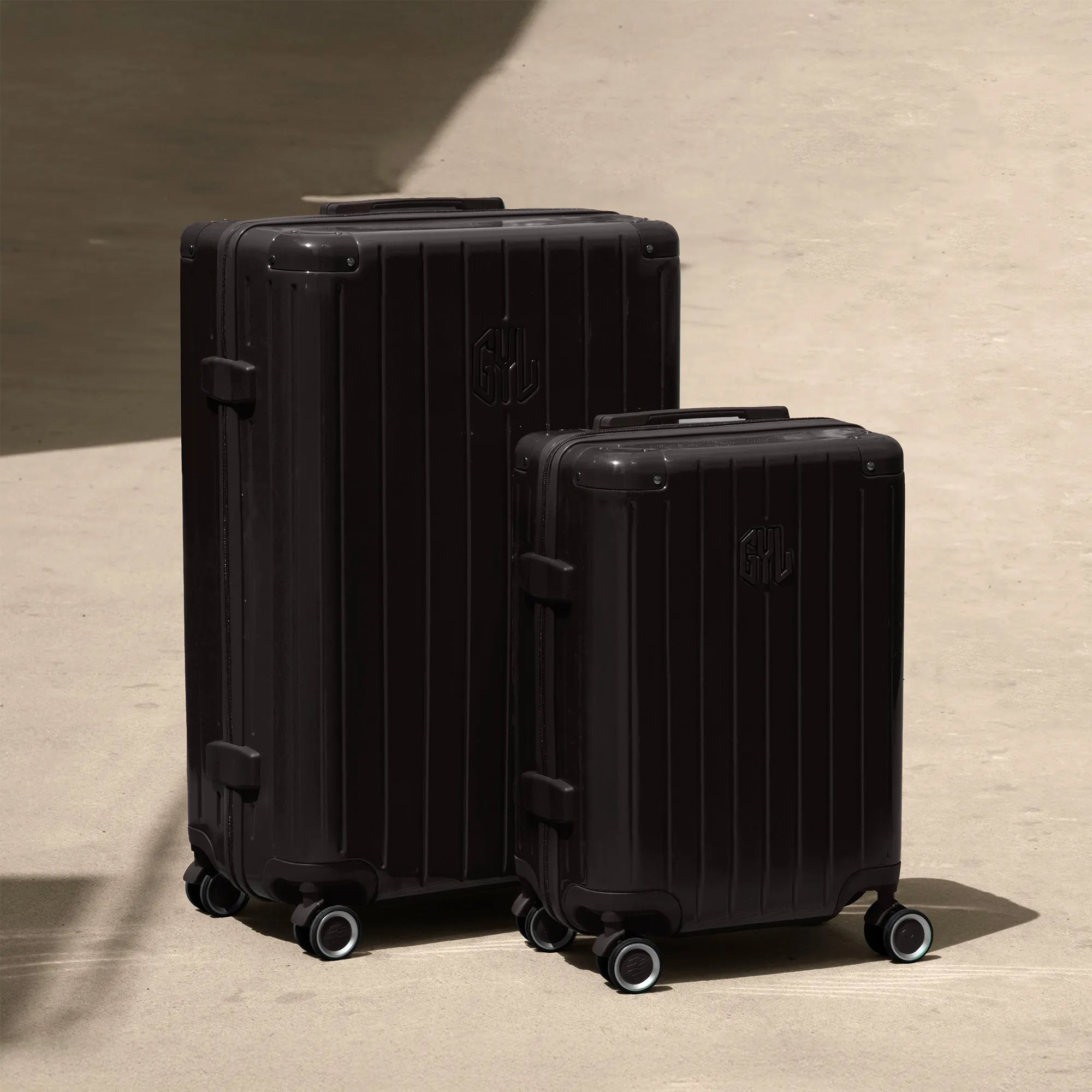 Ensemble de deux valises rigides GYL Intemporelle noir, tailles cabine et soute, posées sur sol béton.