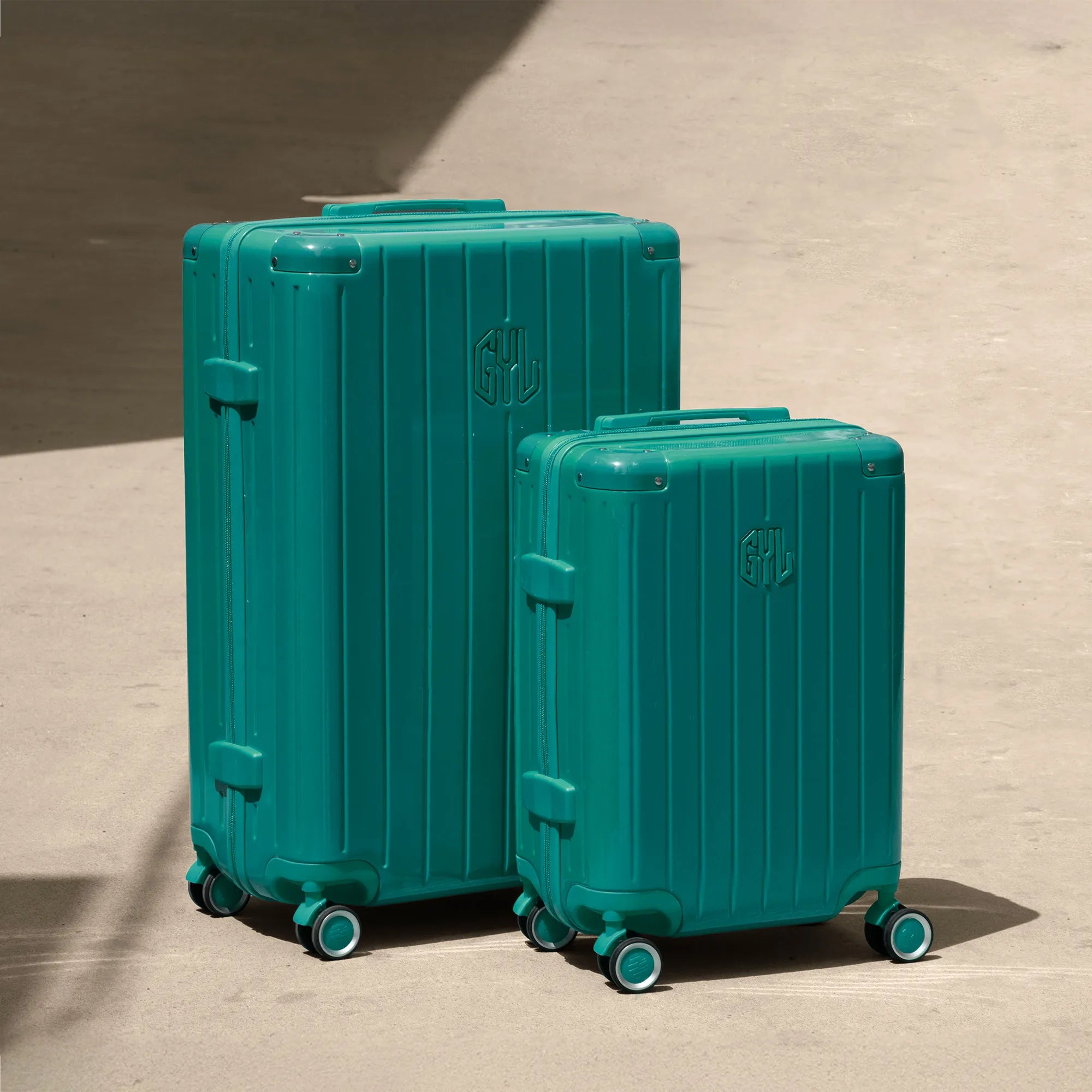 Ensemble de deux valises rigides GYL Intemporelle vert d'eau, tailles cabine et soute, posées sur sol béton.