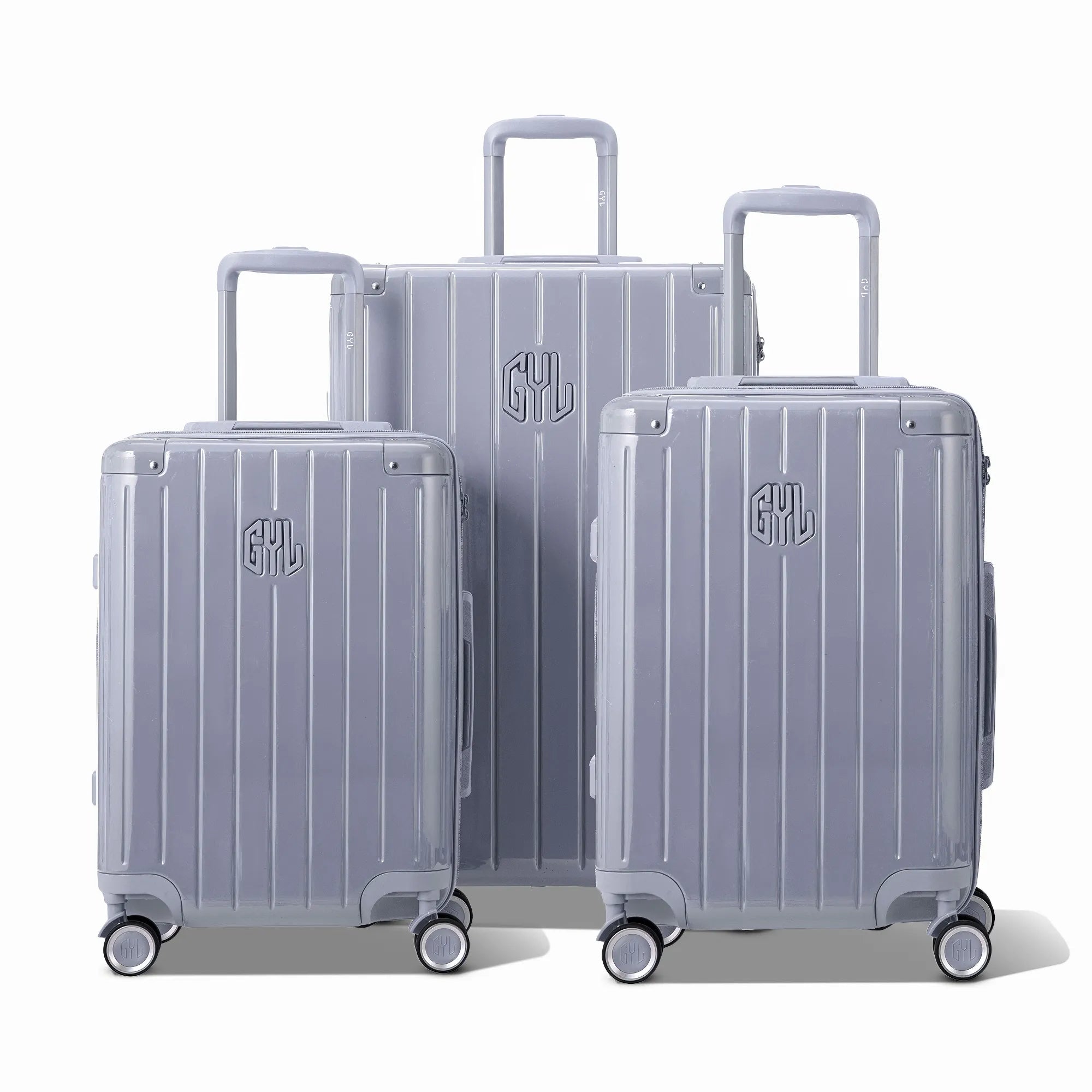 Trois valises rigides GYL Intemporelle argent, format cabine et soute, avec poignée trolley déployée.