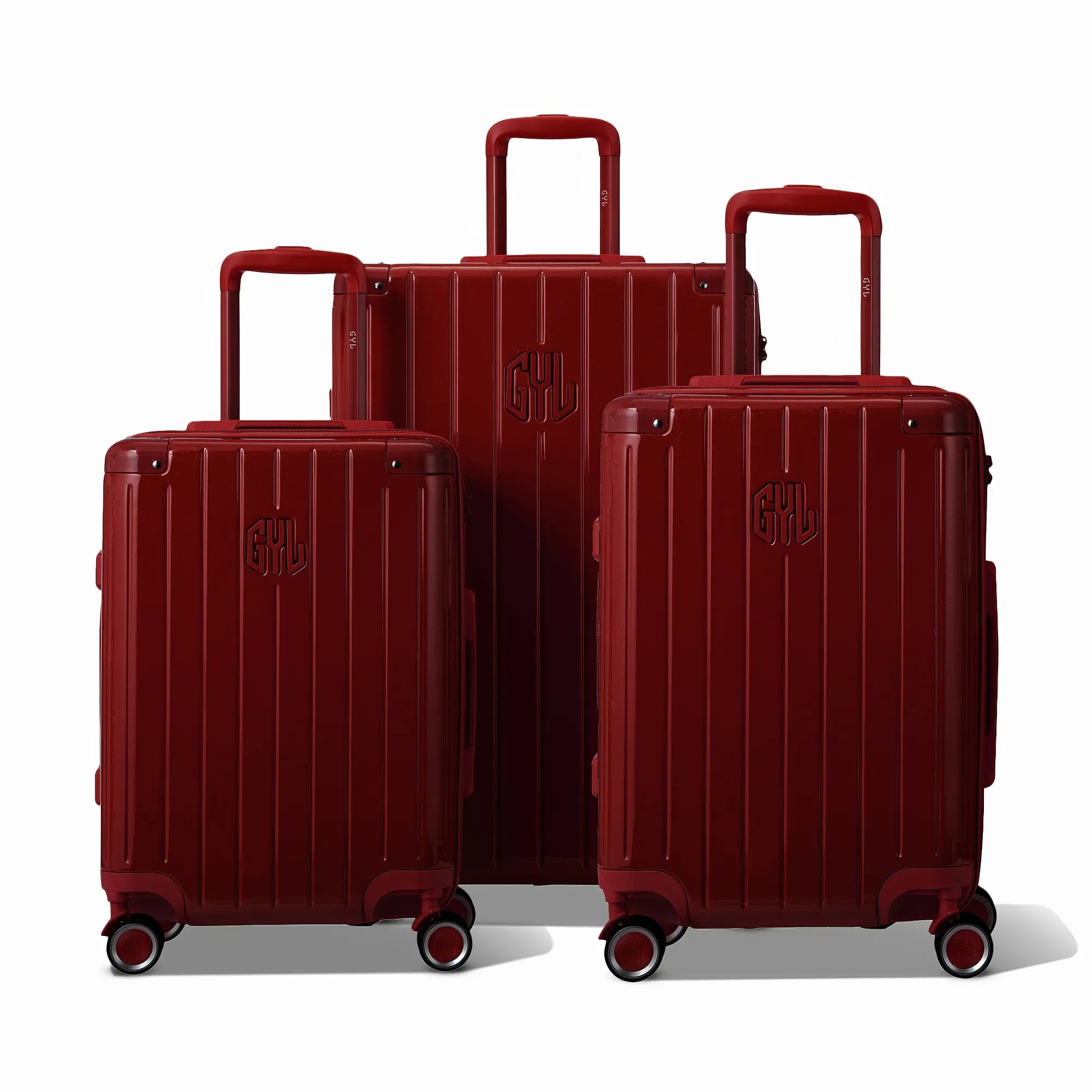 Trois valises rigides GYL Intemporelle rouge foncé, format cabine et soute, avec poignée trolley déployée.