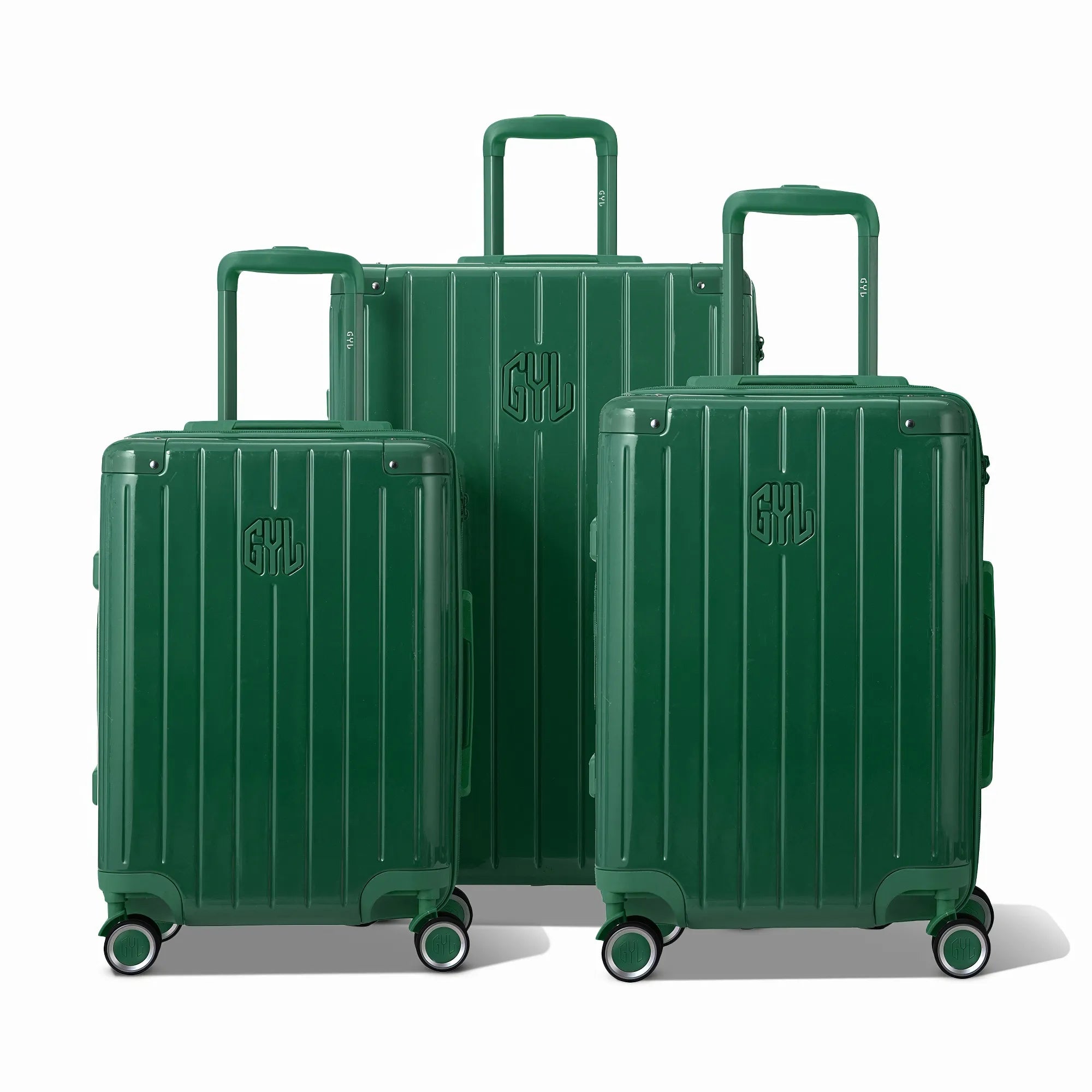 Trois valises rigides GYL Intemporelle sapin, format cabine et soute, avec poignée trolley déployée.