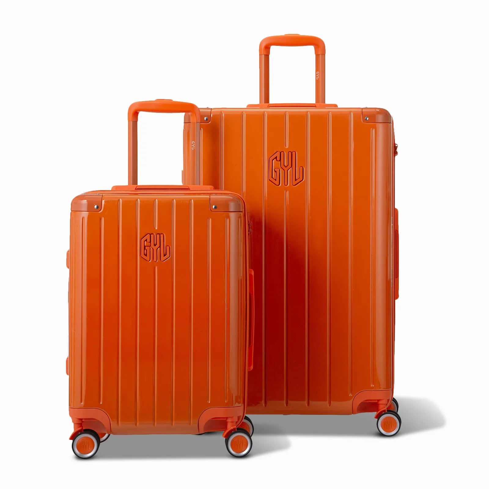 Deux valises rigides GYL Intemporelle orange, 2 formats, avec poignée trolley déployée.