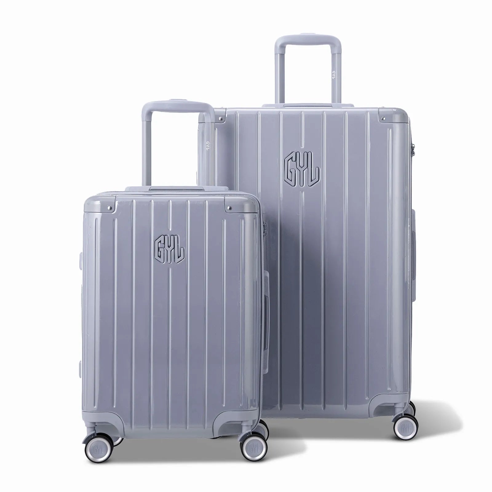 Deux valises rigides GYL Intemporelle argent, format cabine et soute, avec poignée trolley déployée.