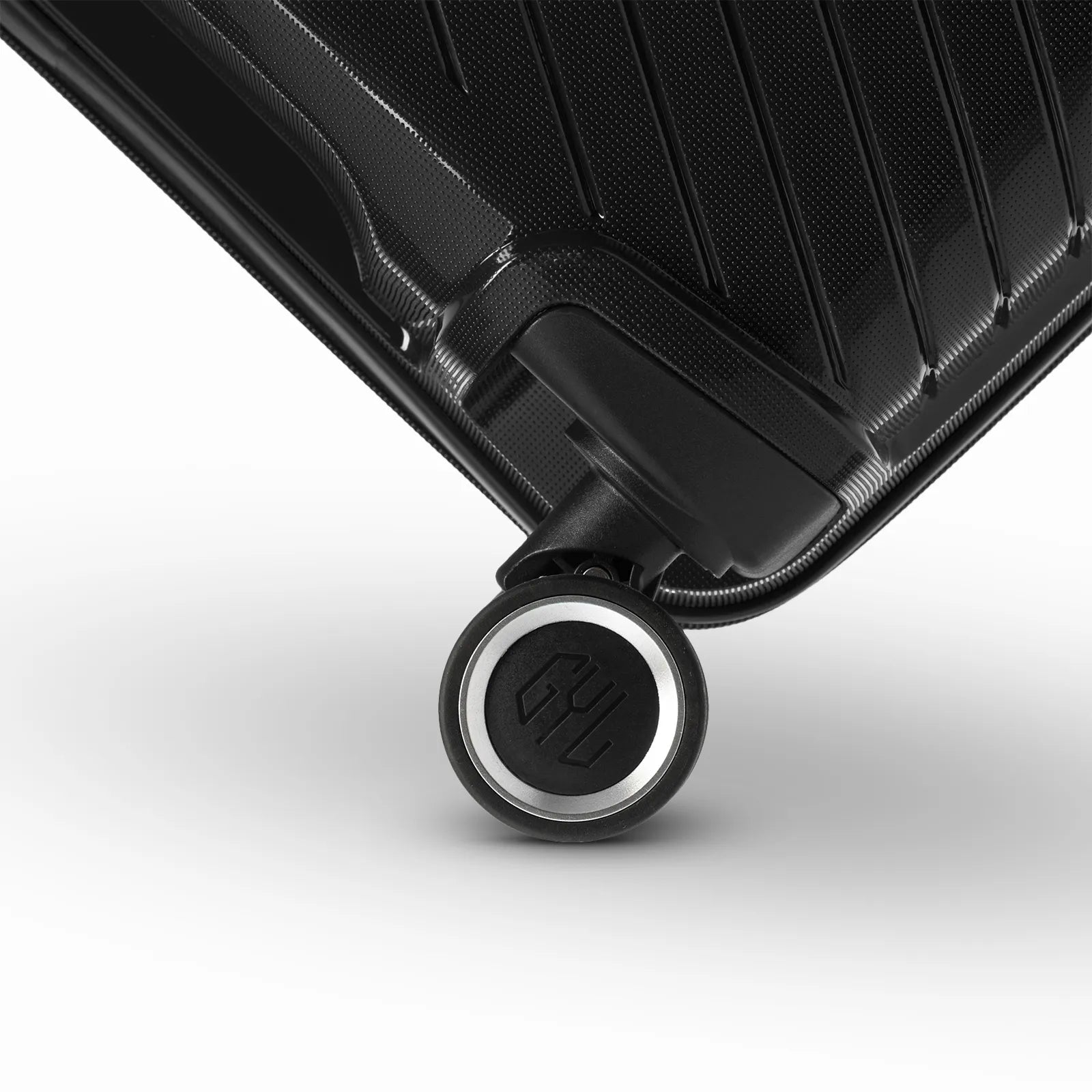 Détail de la roue avec logo GYL sur la valise Signature noire en polypropylène brillant.