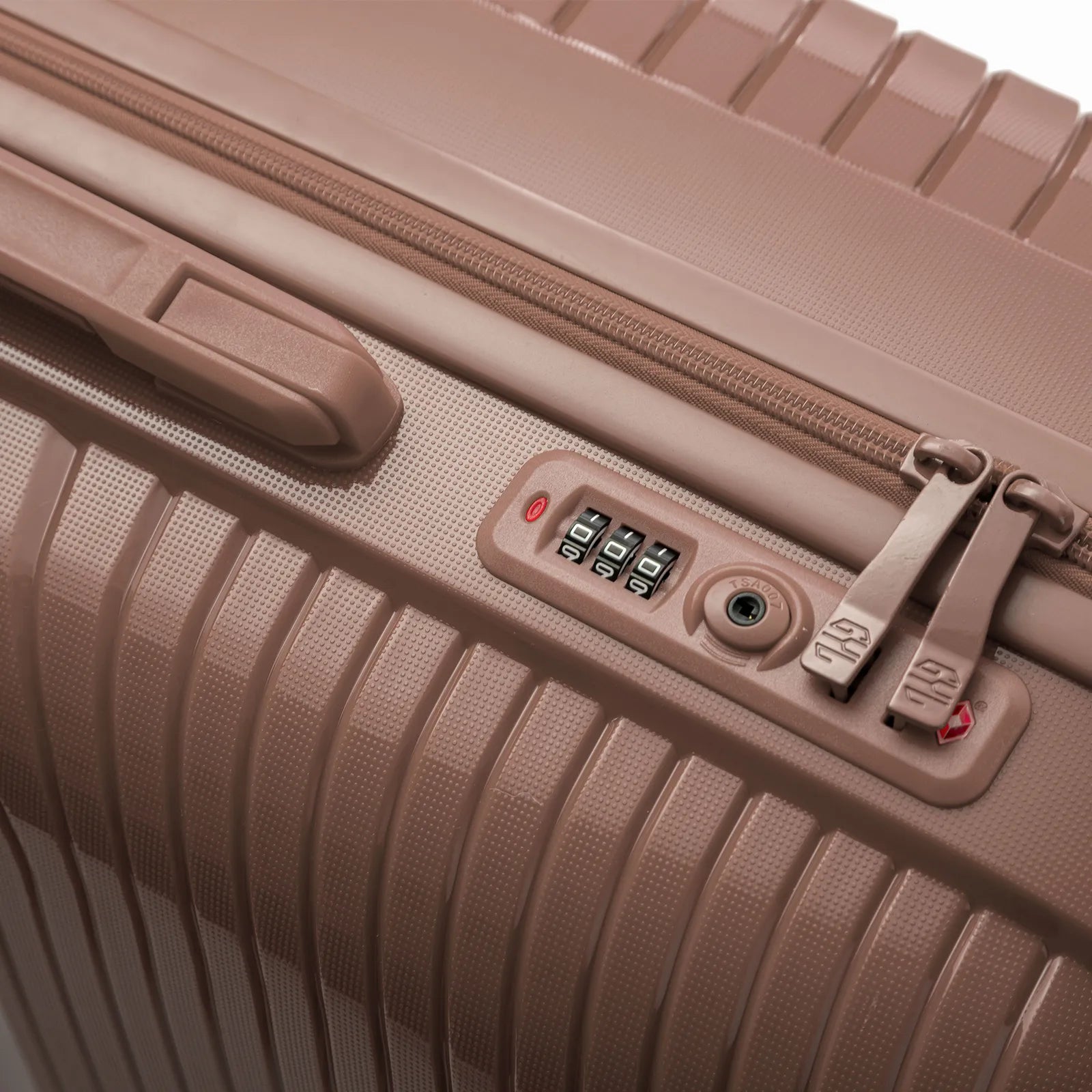 Détail de la serrure TSA intégrée et des curseurs sur la valise Signature champagne.