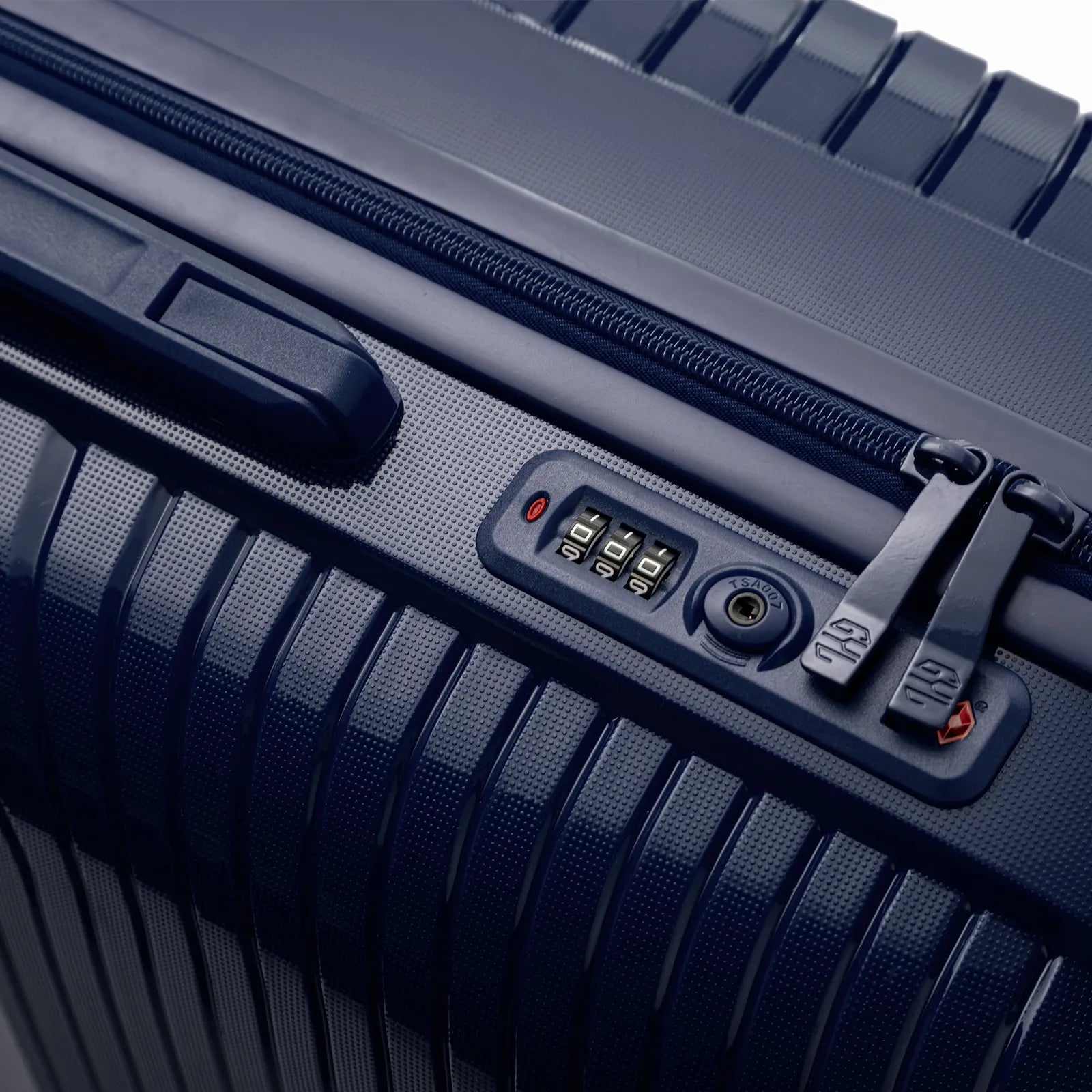 Détail de la serrure TSA intégrée et des curseurs sur la valise Signature marine.
