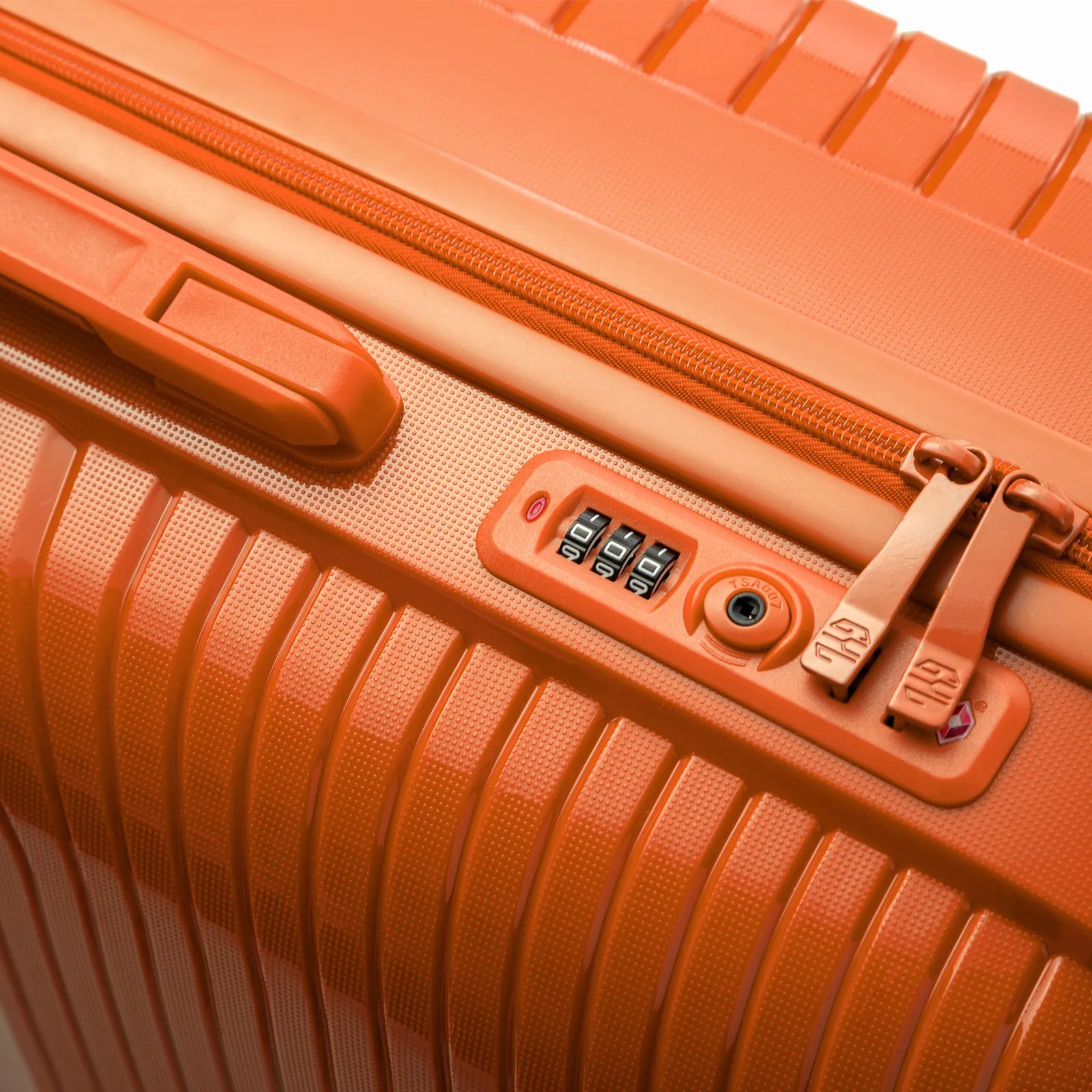 Détail de la serrure TSA intégrée et des curseurs sur la valise Signature orange.