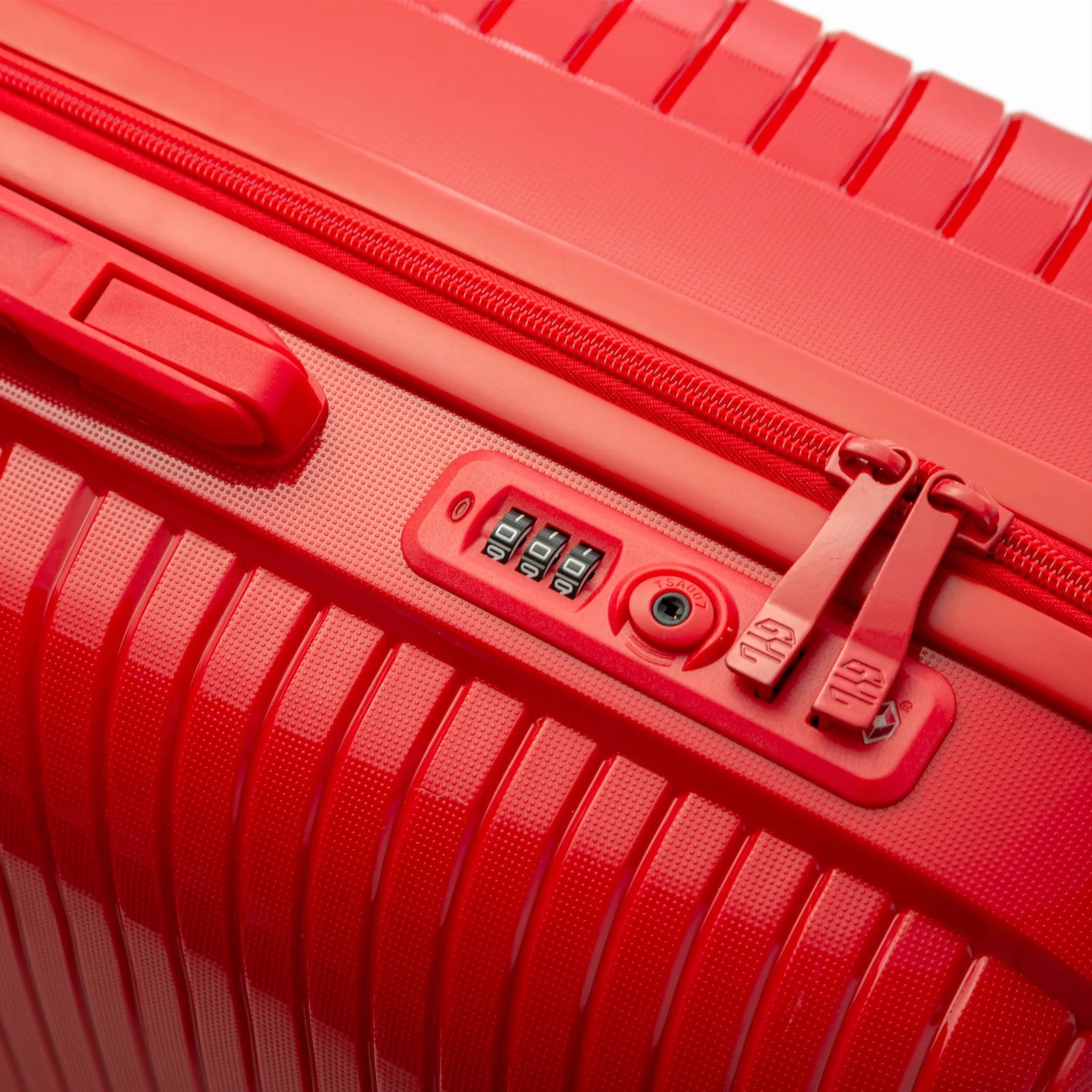 Détail de la serrure TSA intégrée et des curseurs sur la valise Signature rouge.