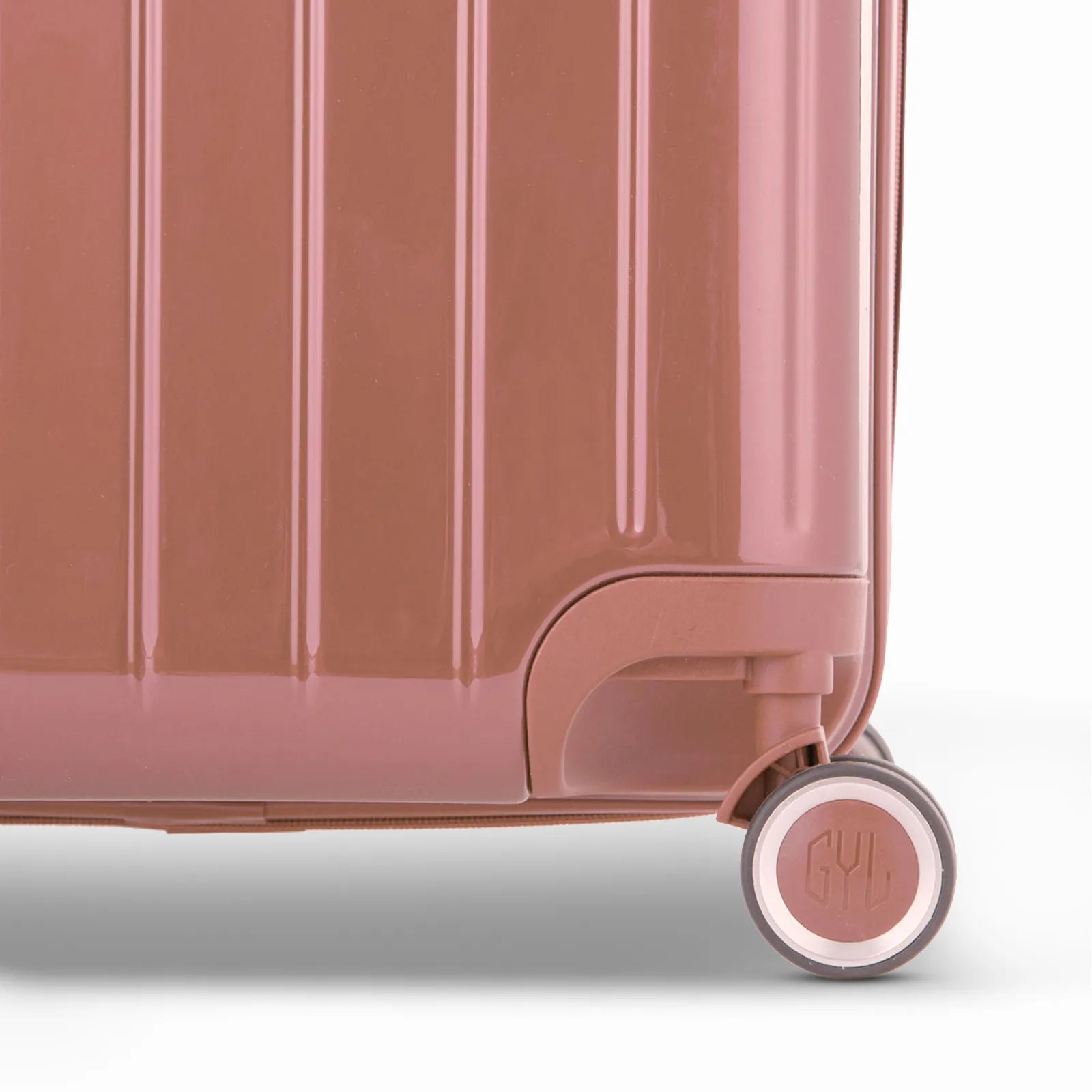 Détail de la roue et du logo GYL sur le bas de la valise trunk rose gold en polycarbonate brillant.