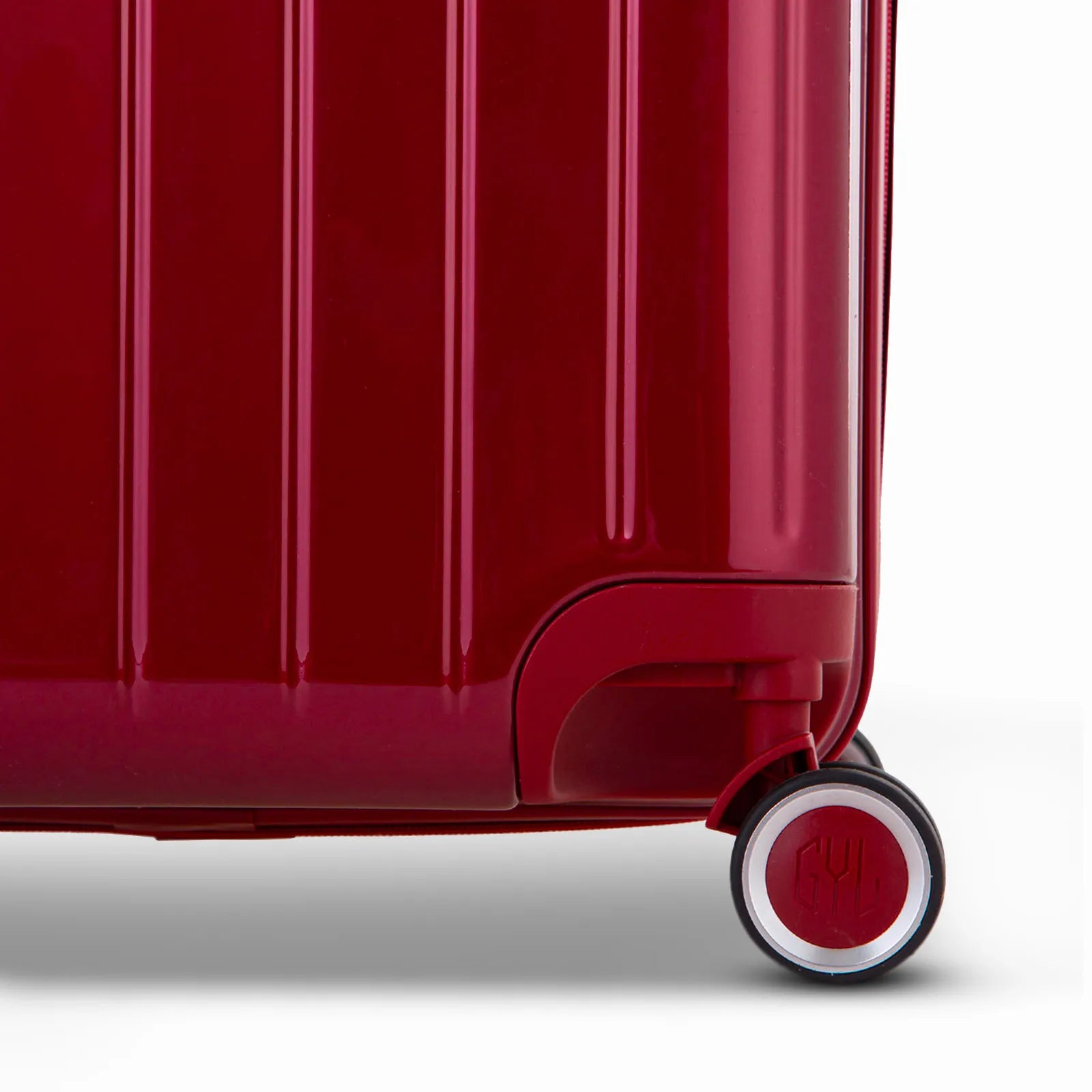 Détail de la roue et du logo GYL sur le bas de la valise trunk rouge foncé en polycarbonate brillant.