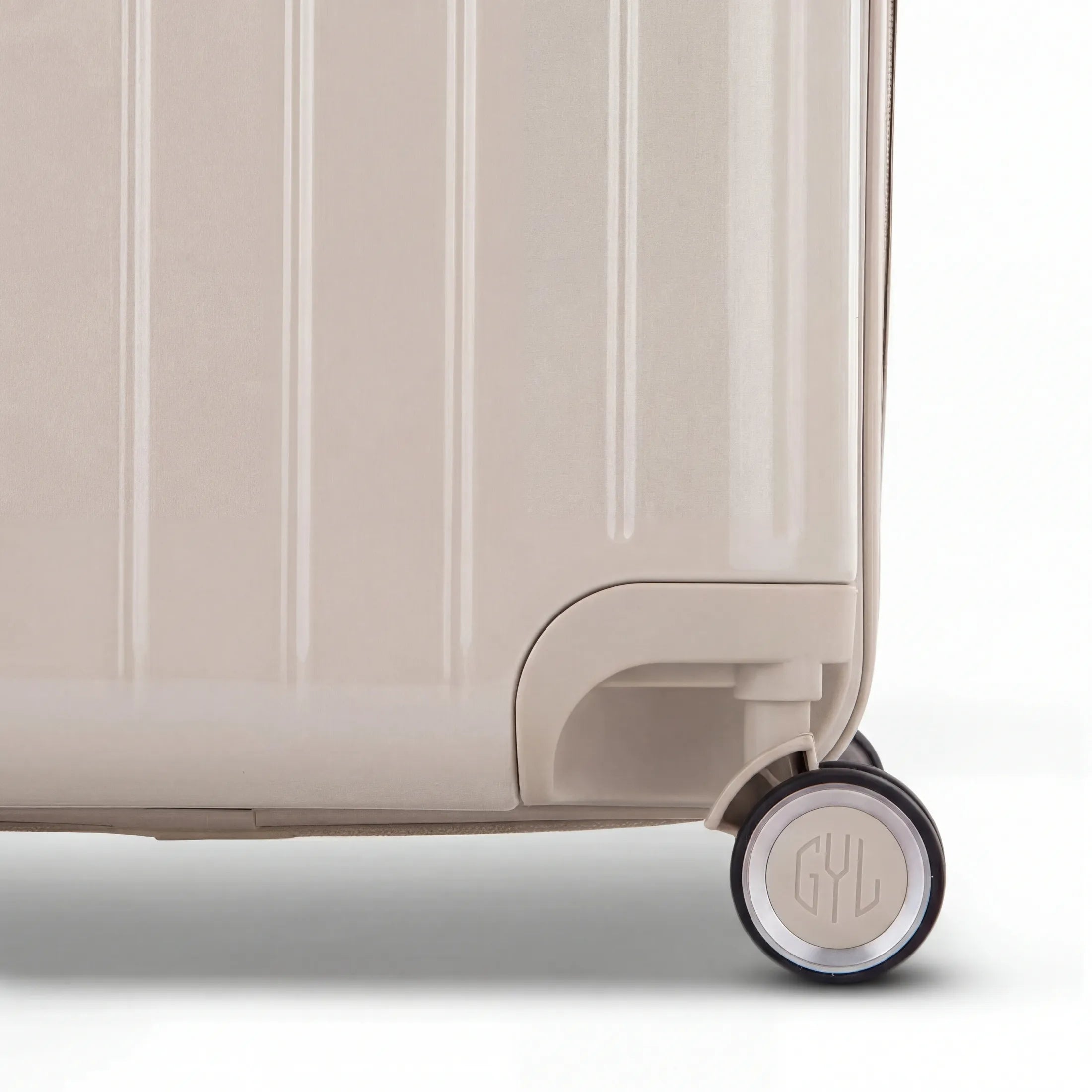 Détail de la roue et du logo GYL sur le bas de la valise trunk nude en polycarbonate brillant.