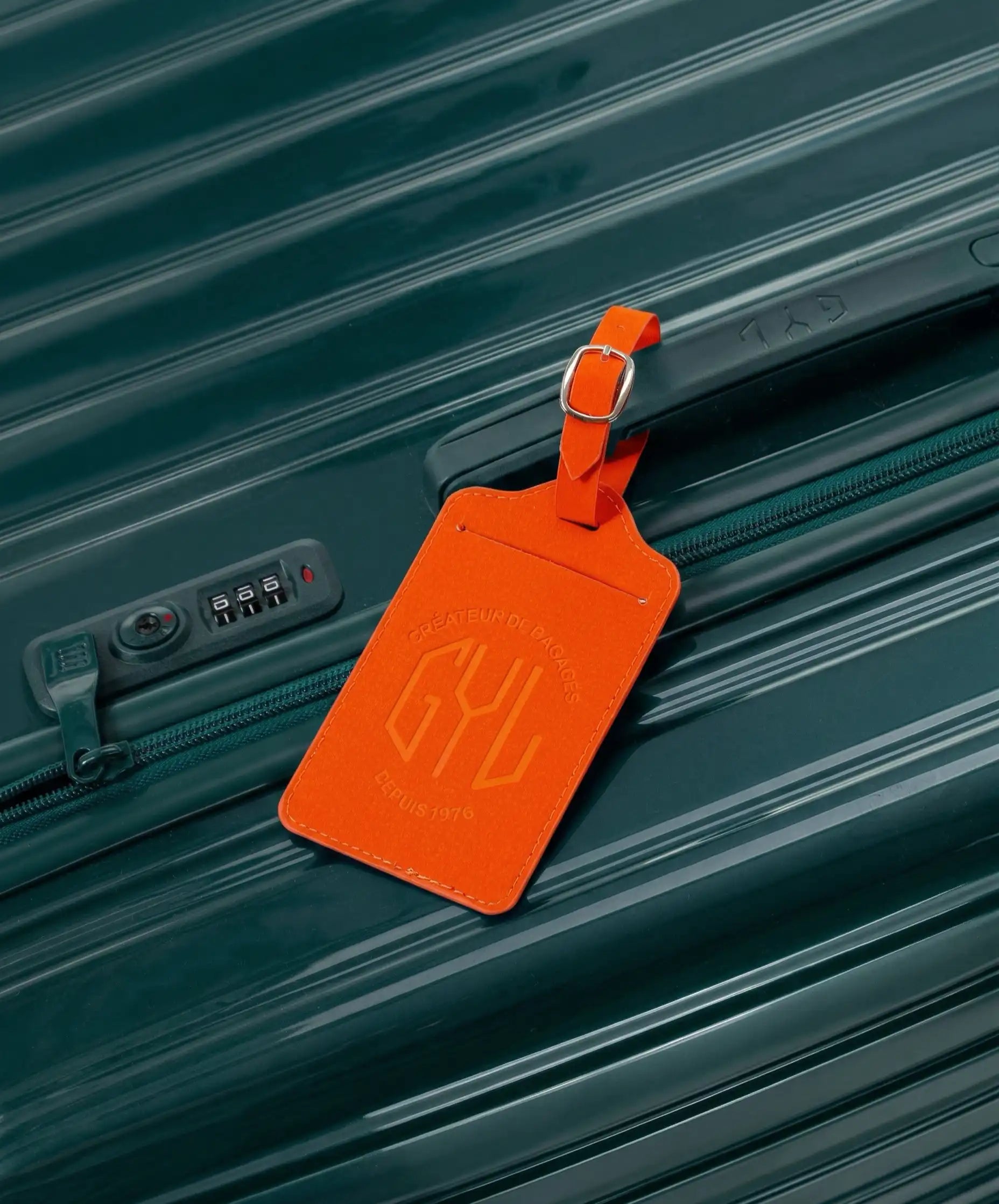 Etiquette a bagages GYL orange accrochee sur valise Intemporelle sapin