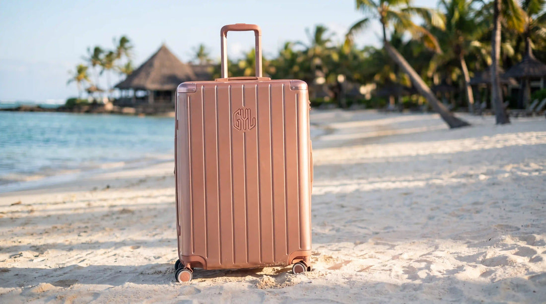 Valise rigide GYL Intemporelle or rose sur une plage de l'île Maurice au bord d'un lagon turquoise