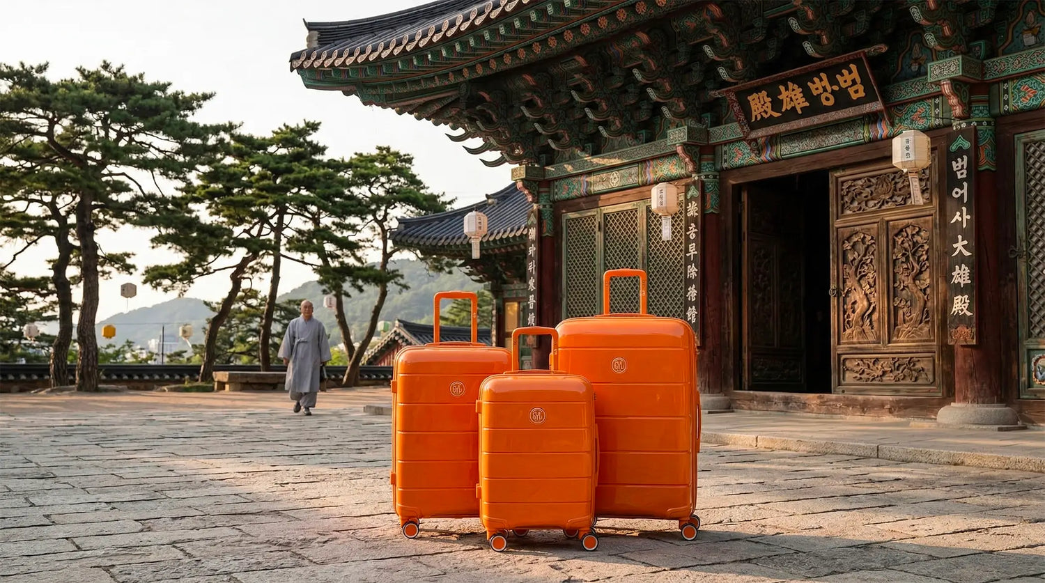 Set de trois valises rigides orange GYL posées dans la cour d'un temple traditionnel lors d'un voyage en Corée du Sud.