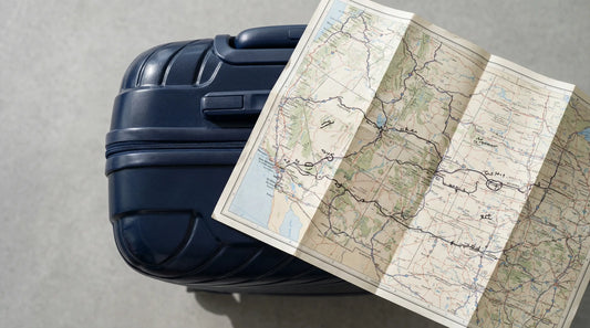Valise rigide signature de voyage avec carte de road trip illustrée, posée dans une pièce lumineuse et élégante