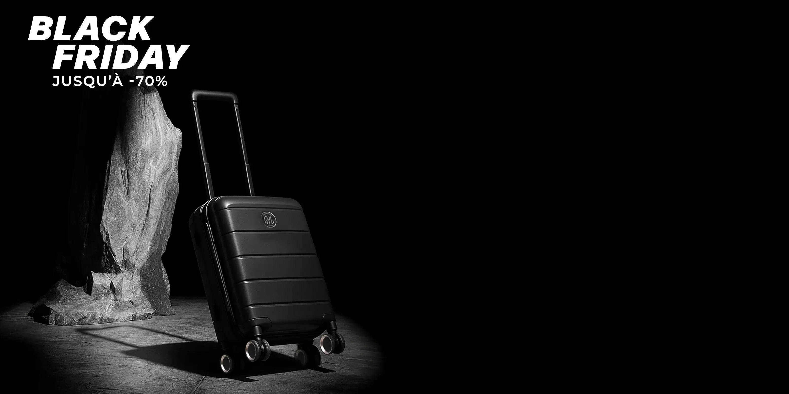 Valise cabine GYL noire en polycarbonate posée devant un rocher, visuel Black Friday jusqu’à 70 pour cent en ambiance studio noir.