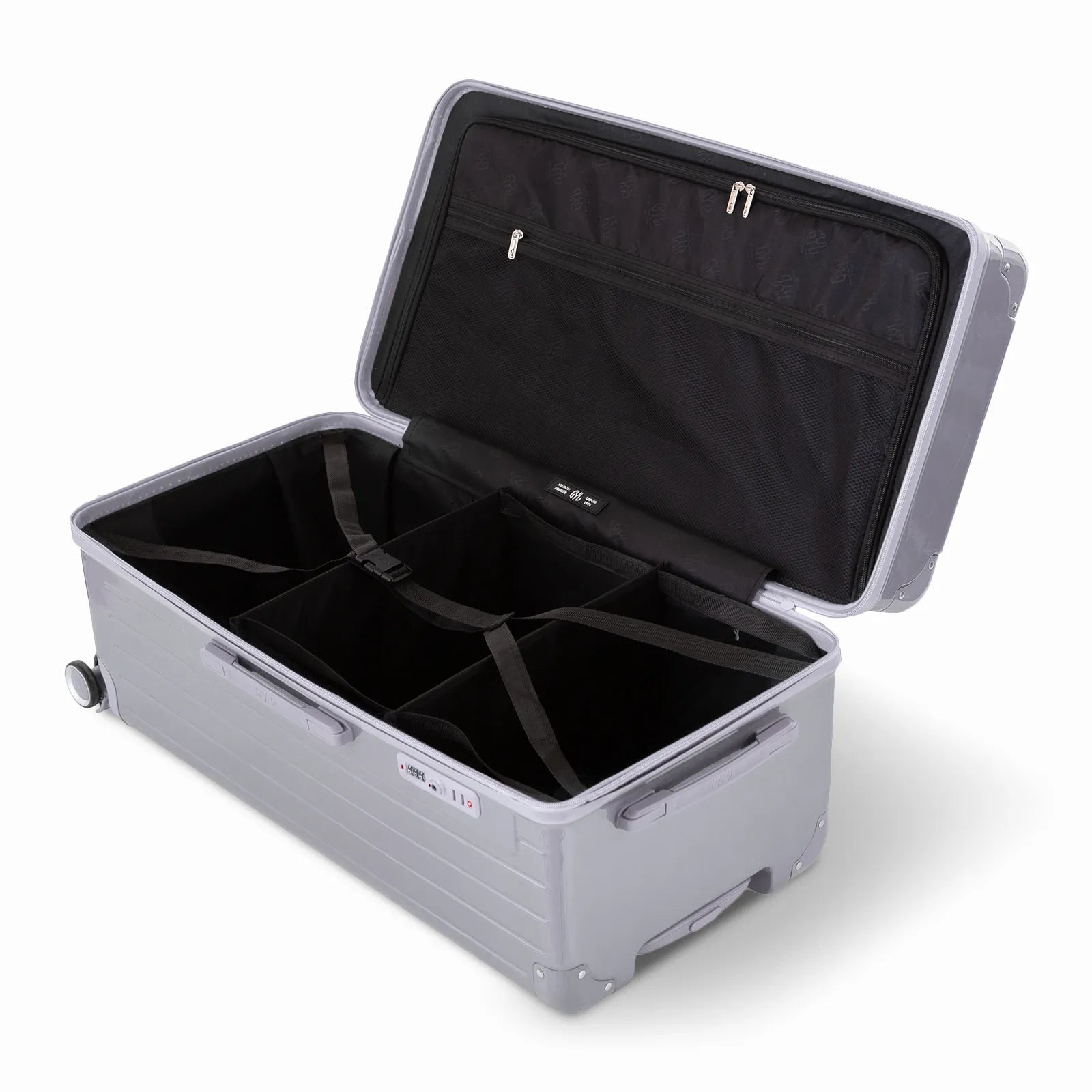 Intérieur de la valise trunk GYL XL argent ouvert, avec sangles croisées et compartiments de rangement.