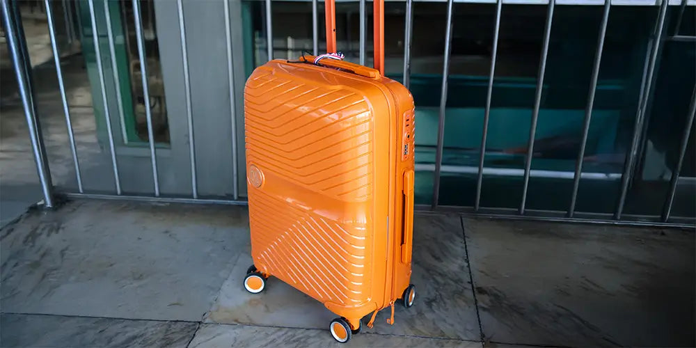 Valise cabine rigide GYL en polycarbonate orange, compacte et légère, équipée de quatre roulettes multidirectionnelles pour voyager facilement.
