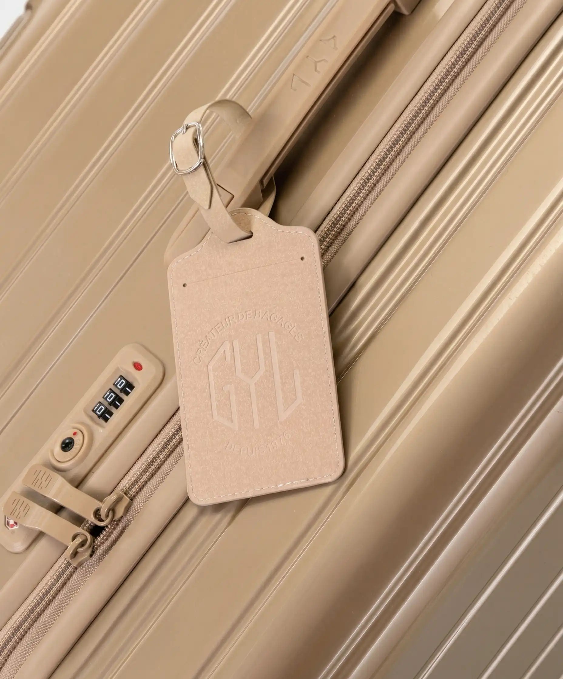 Etiquette a bagages GYL champagne accrochee sur valise Intemporelle champagne