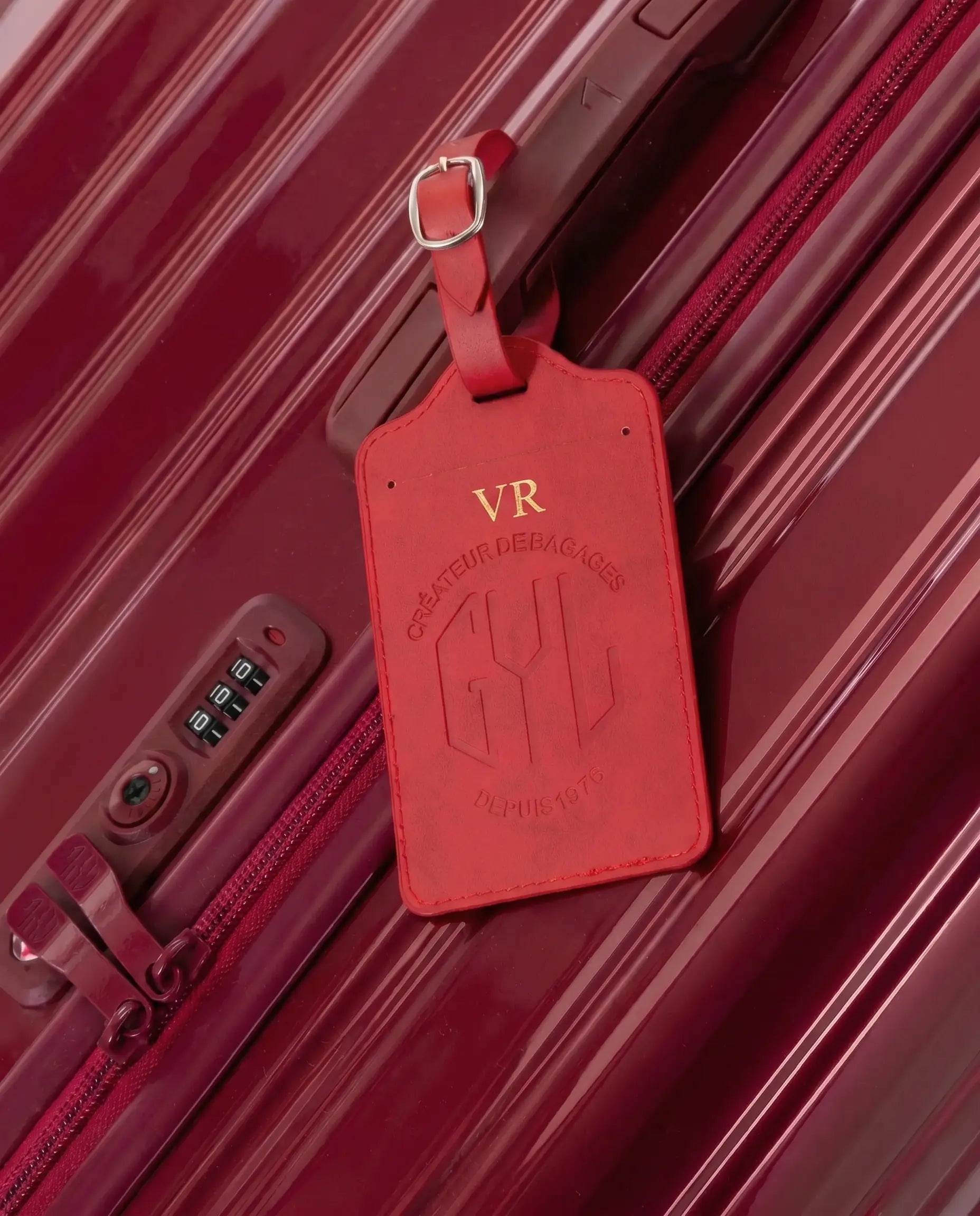 Etiquette a bagages GYL personnalisee initiales VR en feuille d'or, accrochee a une valise bordeaux
