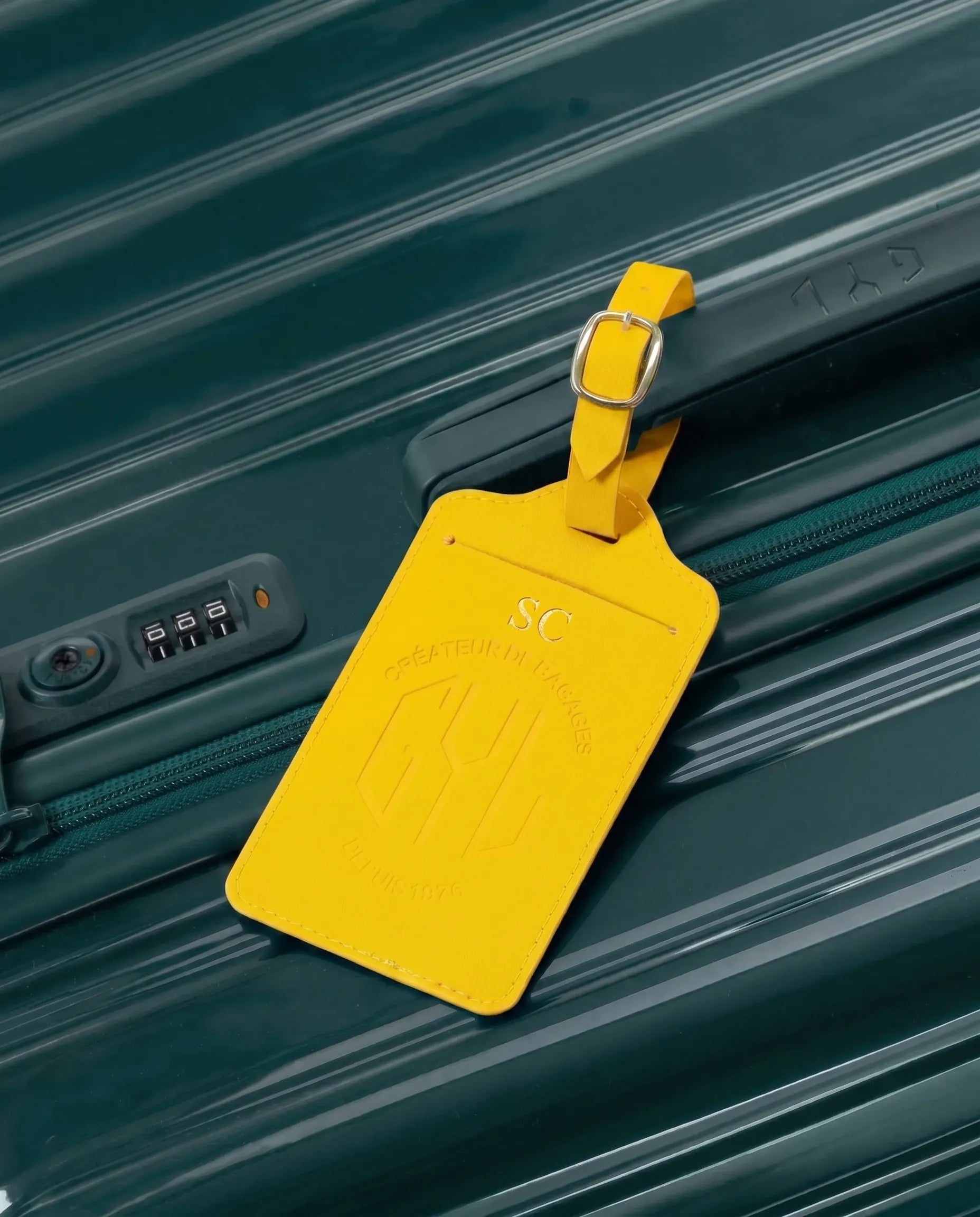Etiquette a bagages GYL personnalisee initiales SC en feuille d'or, accrochee a une valise jaune