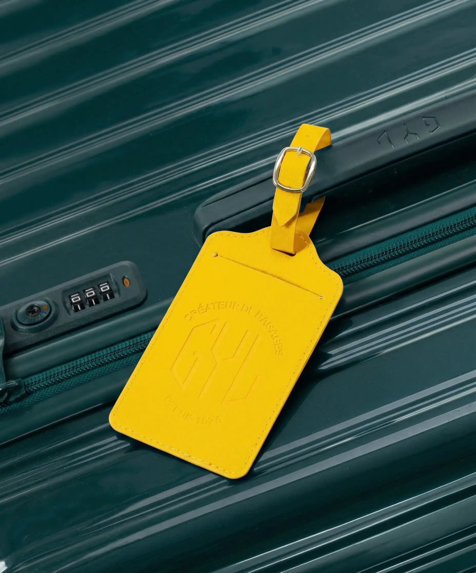 Etiquette a bagages GYL jaune accrochee sur valise Intemporelle sapin