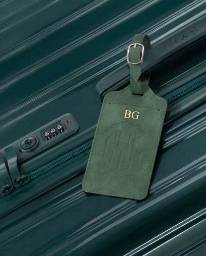 Etiquette a bagages GYL personnalisee initiales BG en feuille d'or, accrochee a une valise vert sapin
