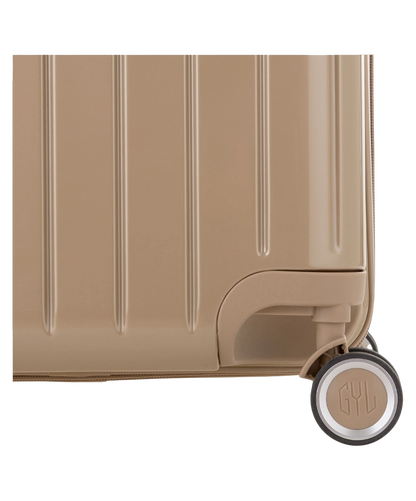 Valise Trunk XL Intemporelle GYL en polycarbonate 78 cm coloris champagne gros plan sur une roulette double 360 degres siglee GYL